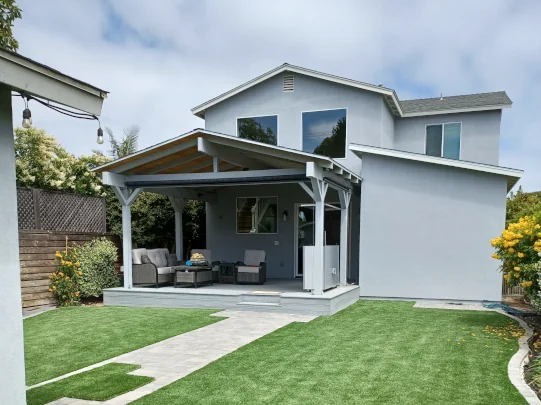 Custom covered deck in Coronado featuring a vaulted wood ceiling, exposed beams, artificial turf, and an outdoor living space.