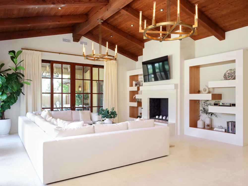 San Diego living room renovation featuring exposed wood beams, a cream sectional sofa, built-in entertainment center, and light tile flooring.
