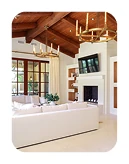 San Diego living room renovation featuring exposed wood beams, a cream sectional sofa, built-in entertainment center, and light tile flooring.